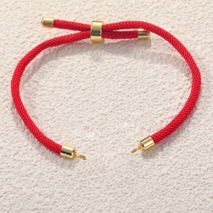Adjustable red Milan cord bracelet with gold-plated metal accents on textured background
