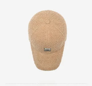 Top view of beige teddy fleece baseball cap showing soft texture and letter embroidery