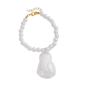 Dettaglio del bracciale di perle con ciondolo a forma di gatto bianco in guscio trasparente