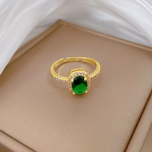 Detail of an adjustable gold sapphire ring with green stone and sparkling zircon accents