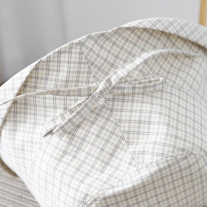 Close-up of checkered fabric hat featuring a decorative bow tie and rolled edge detail