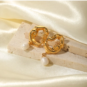 Detailed macro of gold-plated lava texture earrings featuring hanging freshwater pearls