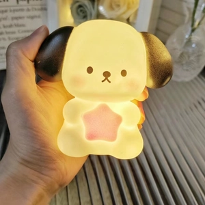 Detailed view of a hand holding a glowing cartoon dog night light with a pink star