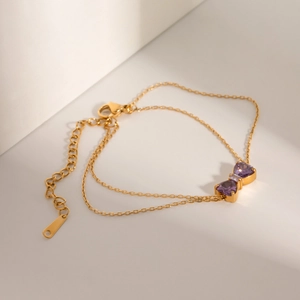Detailed macro shot of 18k gold butterfly bracelet with purple zircon on double chains