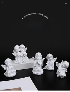 Detail of five white resin angel figurines in various praying and sitting poses on black base