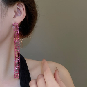 Dettaglio degli orecchini a nappine con strass rosa e design geometrico a sbalzo