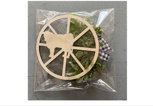 Macro detail of rustic wooden cow wreath with greenery and buffalo plaid bow decoration