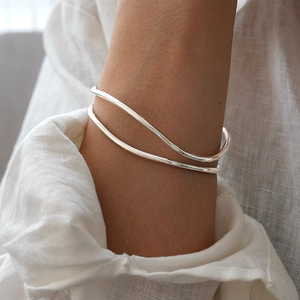 Macro shot of silver minimalist wavy double-layer open bangle on a model arm