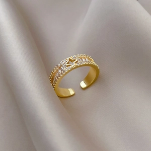 Detaillierte Nahaufnahme eines goldenen Kleeblatt-Rings mit Zirkonia auf Seidenstoff