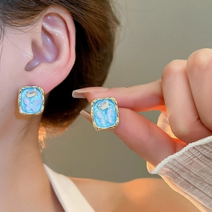 Detailed close-up of butterfly earrings with gold frame, blue base and clear gems