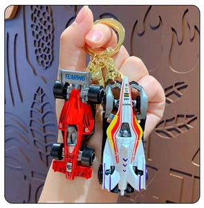 Detail of red and white mini F1 racing car alloy keychains held in hand for scale