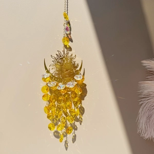 Detail of sun and moon crystal suncatcher hanging with golden metal and amber beads