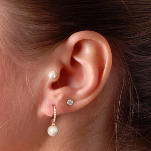 Close-up of S925 silver gold-plated pearl and diamond stud earrings on model's ear