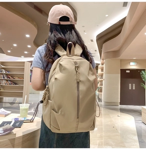 Minimalist beige large capacity backpack worn by person in a cozy bookstore background