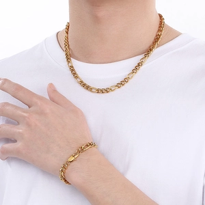 Dettaglio del set collana e bracciale a maglia cubana dorata indossato su t-shirt bianca