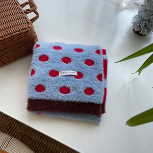 Detail of soft plush light blue scarf with red polka dots and dark brown hem
