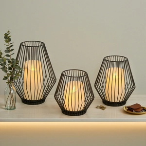 Three Nordic black metal wire candle holders with warm LED candles on a wooden table
