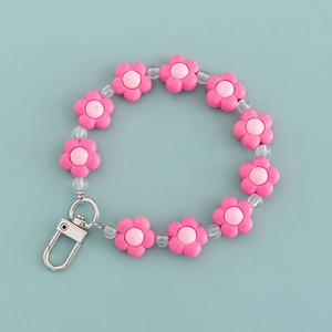 Roze bloem sleutelhanger met transparante kralen en zilveren metalen sluiting op blauw