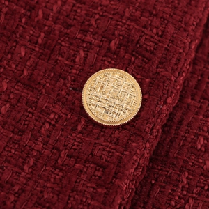 Close-up of vintage red tweed dress with an embossed golden woven texture button