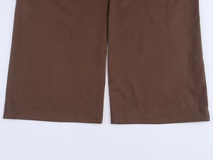 Detailed view of dark brown wide-leg trousers hem showing premium fabric texture
