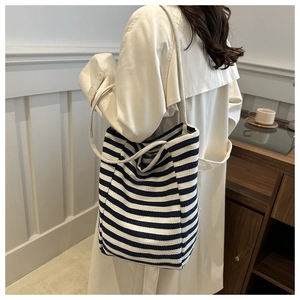 Canvas tote bag with navy and white stripes shown on model in a minimalist setting