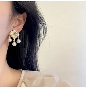 Close-up of elegant pearl cluster earrings with gold base worn by a female model