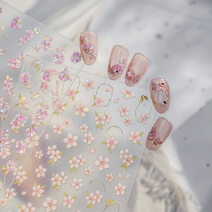 Macro detail of pink cherry blossom nail stickers with gold foil edges and pearl finish