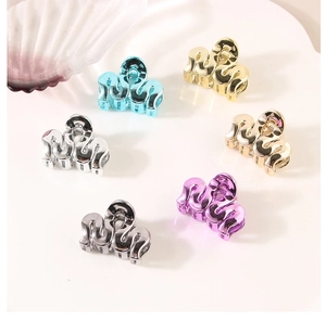 Close-up of small wave-shaped metal hair clips in six metallic colors on white background