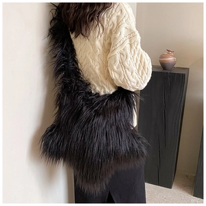 Close-up of fluffy black faux fur crossbody bag texture worn by model in knit sweater