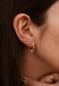 Close-up of gold-plated stainless steel cross earrings set on a model's ear lobe