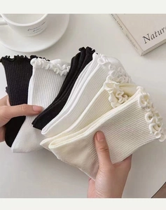 Nahaufnahme des Rüschensaums an gerippten Baumwollsocken in Schwarz und Beige
