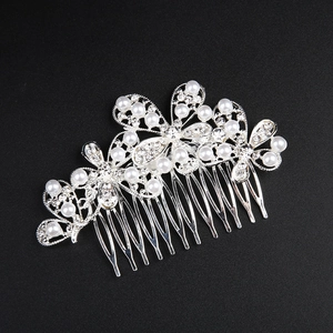 Gros plan d'un peigne de mariée avec perles blanches et strass brillants sur fond noir