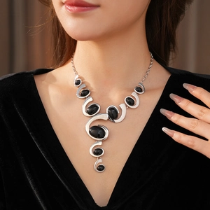 Detail of silver spiral necklace with black oval gemstone on model neck