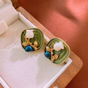 Detailed close-up of vintage tulip floral studs with green enamel in a wooden jewelry box