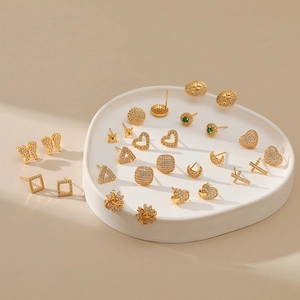 Detail of gold-plated stud earrings set with micro-paved cubic zirconia and green accents