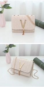 Detail of woven straw bag with gold V-shaped crystal buckle and tassel chain strap
