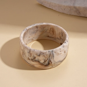 Detailed close-up of wide resin bangle with brown marble texture on a stone base