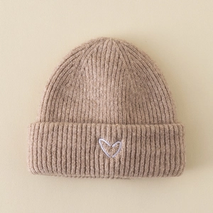Detail of khaki ribbed knit beanie featuring a small white embroidered heart on the cuff