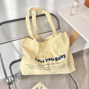 Detail of canvas tote bag with Love you Baby print hanging on a modern chair