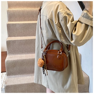 Brown vintage square handbag with detachable strap and teddy bear charm shown on a model