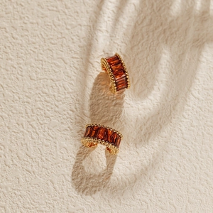 Macro shot of 18K gold-plated ear cuffs with amber zircon inlay and beaded edge detail