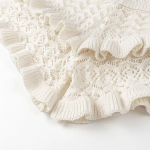 Close-up of cream knit lace texture featuring elegant ruffled edges and hollow-out details