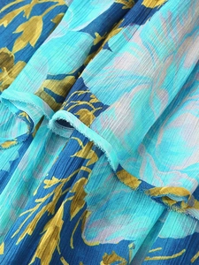 Macro shot of sky blue pleated chiffon dress with yellow floral print and ruffle edges