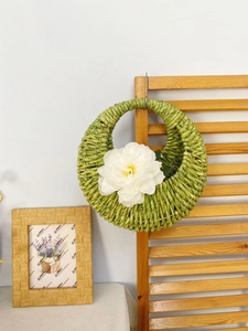 Close-up of green hand-woven wall basket with a large white decorative flower detail
