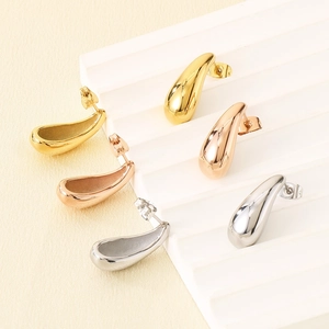 Polished 18k gold and silver drop earrings in three tones on a minimal display