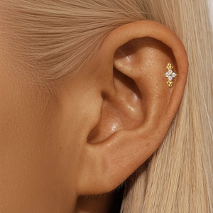 Detailed view of gold moon and star cartilage stud earring worn on the ear helix
