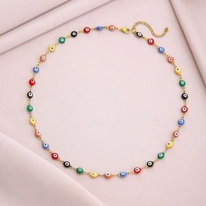 Golden stainless steel evil eye necklace with colorful beads on pink fabric background