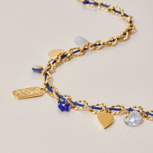 Detail of bohemian gold chain necklace with blue cord, charms and evil eye pendant
