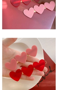 Detail view of red and pink acrylic heart hair clips with golden metal base grips