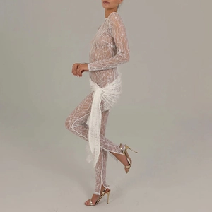 Detail view of white lace jumpsuit featuring waist wrap design and sheer long sleeves